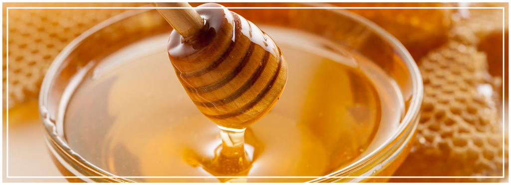 Vasetto con coglimiele ricoperto di miele e tutto intorno alveari di api
